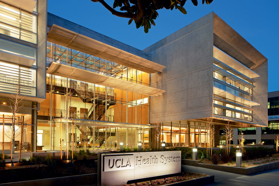 The front of a HUCLA Health building light up at dusk 
